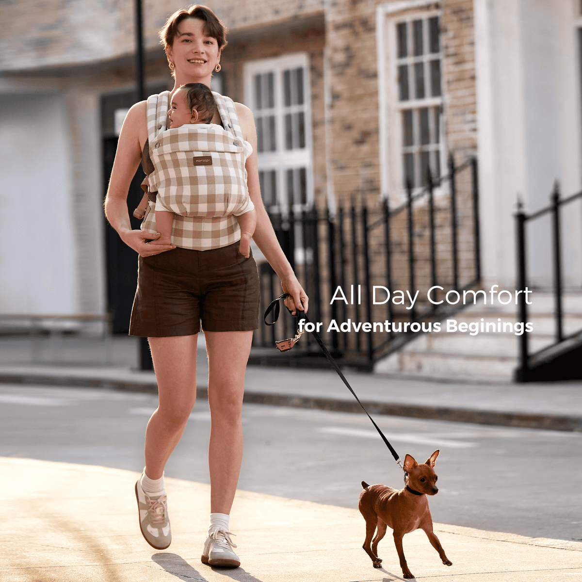Momcozy PureHug baby carrier in beige gingham, all-day comfort for babywearing while walking a dog