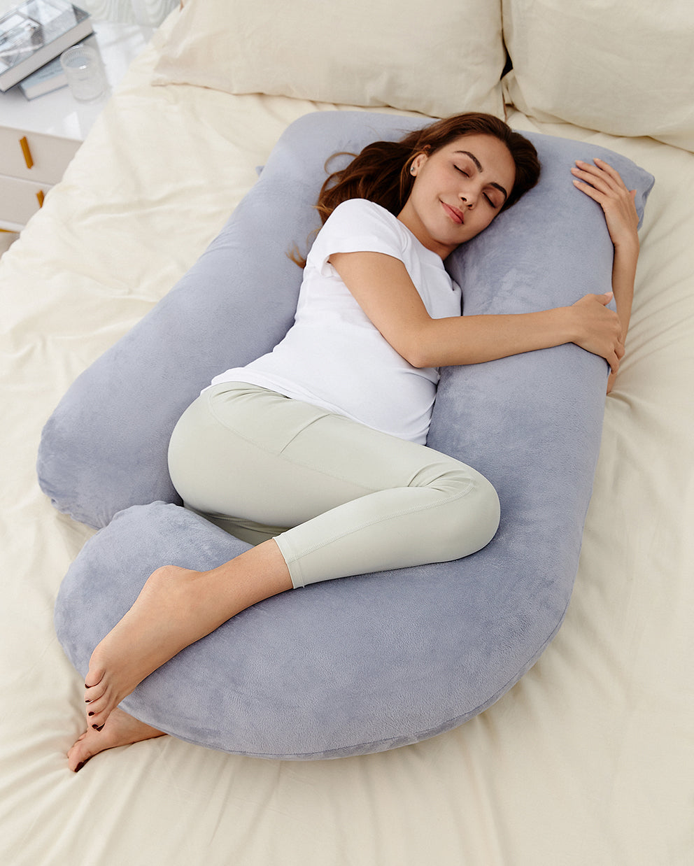 Schwangere schläft seitlich im U-förmigen Momcozy Schwangerschaftskissen im Bett