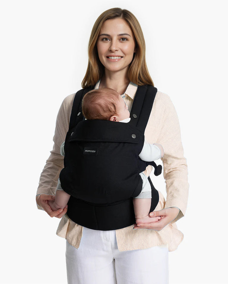 Translation missing: de.Momcozy PureHug Babytrage in Schwarz, von einer Frau mit Neugeborenem getragen